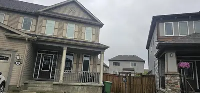 a house with a fence and two houses at Cozy and Affordable Apartment - Guesthouse South West Airdrie in Airdrie