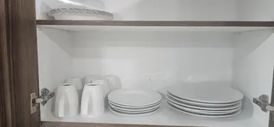 a shelf with white plates and bowls in a cabinet at Cozy and Affordable Apartment - Guesthouse South West Airdrie in Airdrie
