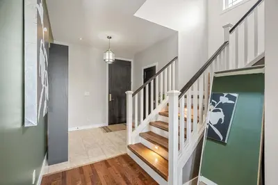 a hallway with a white staircase with a green wall at Luxe & Lake 6BR Getaway Hot Tub Near the Lake in Sylvan Lake