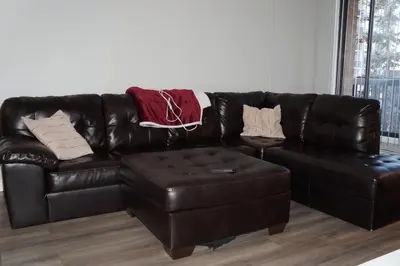 a brown leather couch with pillows and a stool at YYC : 2-Bedroom City Apartment in Calgary