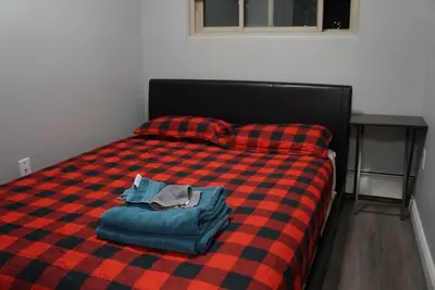 a bed with a red and black checkered blanket at YYC : 2-Bedroom City Apartment in Calgary