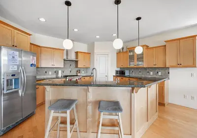 a kitchen with a large island with two bar stools at Full House with Amazing Okanagan Views and Hot Tub in Kelowna