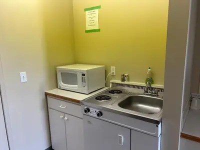 a kitchen with a sink and a microwave at The King's Motel in Sundre