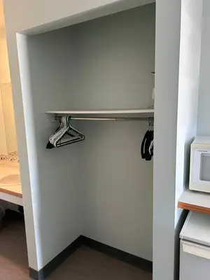a room with a white wall with a shelf and a microwave at The King's Motel in Sundre