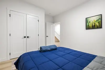 a bedroom with a blue bed and white walls at Lake Community Hideout in Chestermere