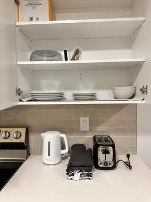 a kitchen counter with a toaster and plates on shelves at 2 Bedroom snug retreat in Livingston Calgary Alberta in Calgary