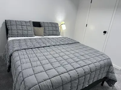 a bedroom with a large bed with a gray blanket at 2 Bedroom snug retreat in Livingston Calgary Alberta in Calgary