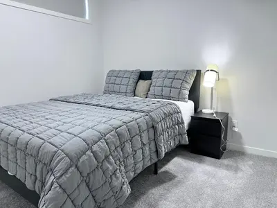 a bedroom with a bed and a lamp on a night stand at 2 Bedroom snug retreat in Livingston Calgary Alberta in Calgary