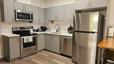 a kitchen with white cabinets and a stainless steel refrigerator at Modern Suite - Separate Entry - Self Check-In in Calgary