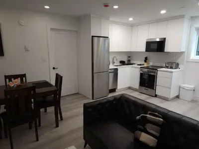 a kitchen with a couch and a table and a refrigerator at vistaeast 1-Bedroom Condo Rupert st in Vancouver
