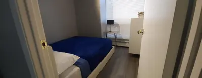 a small bedroom with a blue bed and a window at Wildrose : 2-Bedroom City Apartment in Calgary