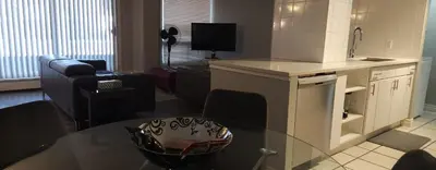 a kitchen and living room with a table and a couch at Wildrose : 2-Bedroom City Apartment in Calgary