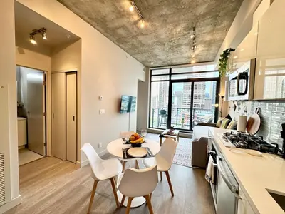 a kitchen and living room with a table and chairs at Elegant, Comfy & Sophisticated MetroLux Downtown Suite in Calgary