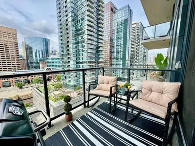 a balcony with two chairs and a table and some buildings at Elegant, Comfy & Sophisticated MetroLux Downtown Suite in Calgary