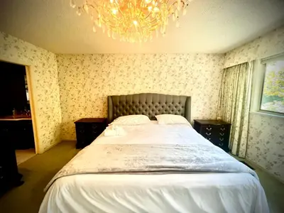 a bedroom with a large bed with a chandelier at Spacious place Close to UBC -1 in Vancouver