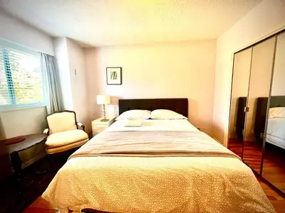 a bedroom with a large bed and a chair at Spacious place Close to UBC -1 in Vancouver