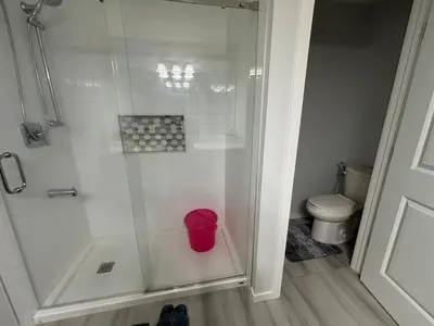a bathroom with a shower with a red trash can at Zillion’s Joy in Calgary