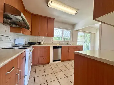 a large kitchen with wooden cabinets and white appliances at Spacious 5 Bedroom House Near YVR Airport, Transit & Shopping in Richmond