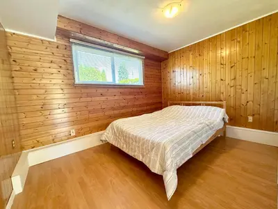 a bedroom with a bed in a room with wooden walls at Spacious 5 Bedroom House Near YVR Airport, Transit & Shopping in Richmond