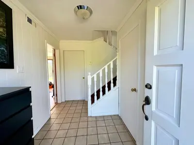 a hallway with a white door and a staircase at Beautiful Place with Kitchen, Washing Machine and Internet Near YVR Airport, Transit and Shopping Mall in Richmond