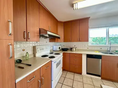 a kitchen with wooden cabinets and a white stove top oven at 2 Bedrooms Garden Suite with Living Room, Kitchen and Laundry near YVR Airport, Transit and Shopping Mall in Richmond