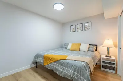 a bedroom with a bed and a lamp on a wooden floor at New 1 bdr basement apartment in Calgary