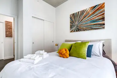 a bedroom with a large white bed with colorful pillows at Modern 1BR plus Den Condo for 4 guests Great Views and Balcony in Calgary