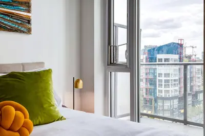 a teddy bear sitting on a bed next to a window at Modern 1BR plus Den Condo for 4 guests Great Views and Balcony in Calgary