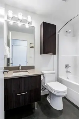 a bathroom with a toilet and a sink and a mirror at Modern 1BR plus Den Condo for 4 guests Great Views and Balcony in Calgary
