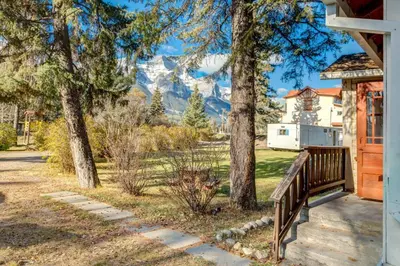 a house with a porch with mountains in the background at Huckleberry Lodge Mountain Getaway Near Banff in Canmore