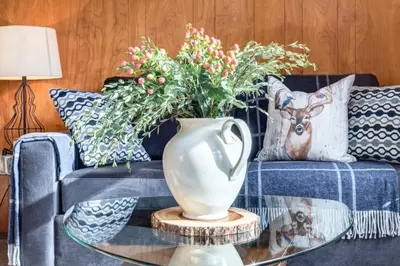 a blue couch with a vase on a glass table at Huckleberry Lodge Mountain Getaway Near Banff in Canmore