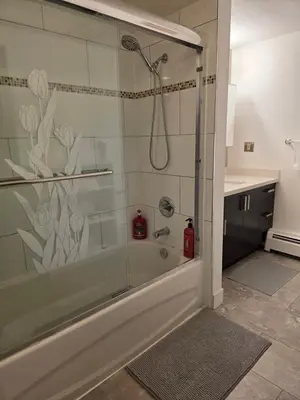 a bathroom with a shower with a glass door at Maplewood Hostel in Vancouver