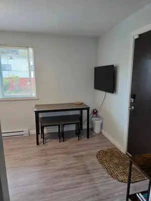 a living room with a table and a tv at Maplewood Hostel in Vancouver