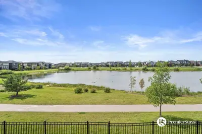 a lake in a park with houses in the background at Luxurious Detached House with Private Garage, Lake View, Central AC & More in Airdrie