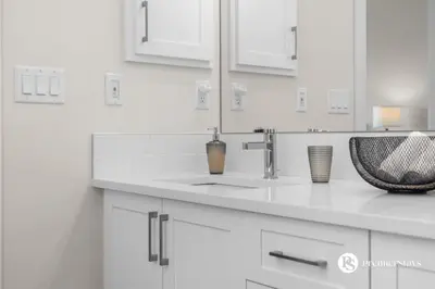 a white kitchen with a sink and a mirror at Luxurious Detached House with Private Garage, Lake View, Central AC & More in Airdrie