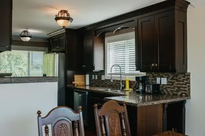 a kitchen with dark wood cabinets and a sink at Serene 3BR Cabin on 8 Acre Farm in Mission City