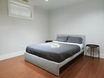 a bed in a room with a white wall at Bright 3-Bedroom Basement Suite with Separate Entrance in Burnaby