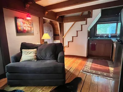 a living room with a couch and a staircase at Malahat Fairyland Cottage in Malahat