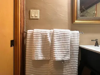 two white towels hanging on a towel rack in a bathroom at Malahat Fairyland Cottage in Malahat