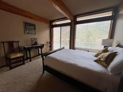 a bedroom with a bed and a chair and a window at Malahat Fairyland Cottage in Malahat