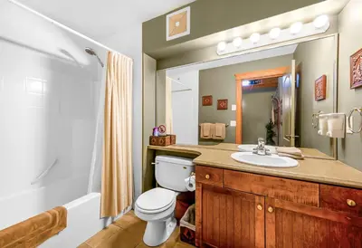 a bathroom with a toilet and a sink and a mirror at Treetops Ski Luxury Townhouse in Big White