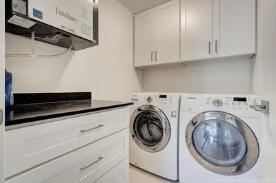 a white laundry room with a washer and dryer at Queens Suite in West Vancouver