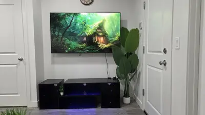 a tv hanging on a wall with a picture of a house at Modern 2BR near Hospital, YMCA, Stores in Calgary