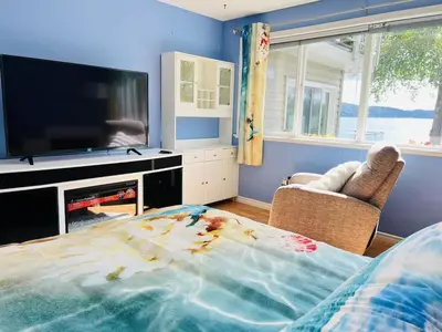 a living room with a large tv and a bed at Stunning oceanfront home 4br3b sunrise beachcombing near Bamberton Park in Mill Bay