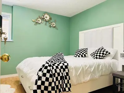 a bedroom with green walls and a bed with black and white pillows at Stunning oceanfront home 4br3b sunrise beachcombing near Bamberton Park in Mill Bay