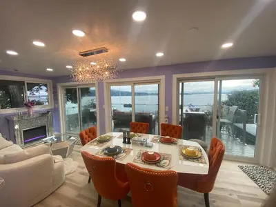 a dining room with a table and chairs and a couch at Stunning oceanfront home 4br3b sunrise beachcombing near Bamberton Park in Mill Bay