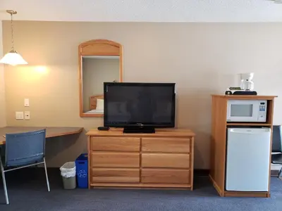 a television on a wooden dresser in a room at Lamplighter Inn in Three Hills