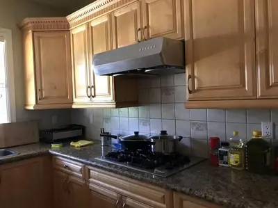 a kitchen with wooden cabinets and a stove with pots and pans at Vancouver Richmond Villa 32 in Richmond