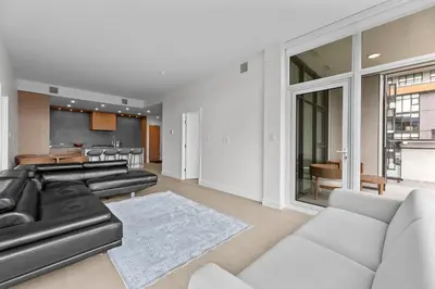 a living room with a black leather couch and a kitchen at Gyro Beach Vacations in Kelowna