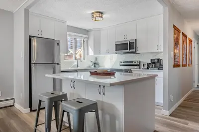 a kitchen with white cabinets and stainless steel appliances at YYC HiddenGem in Calgary